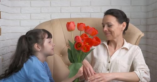 Girl Gives Bouquet of Tulips to Woman