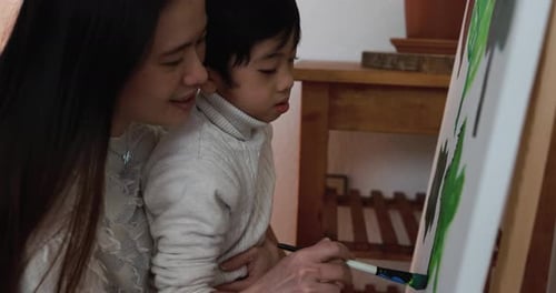 Woman Helps Child Painting at Home