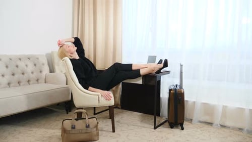 Woman Reclining in Hotel Room with Feet on Desk