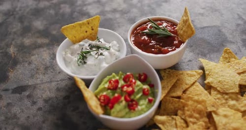 Primer plano de nachos y variedad de salsas sobre una superficie negra