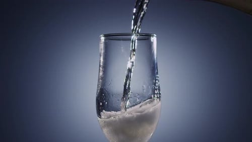 Champagne Wine Is Poured Into Transparent Glass Tumbler. Blue Background