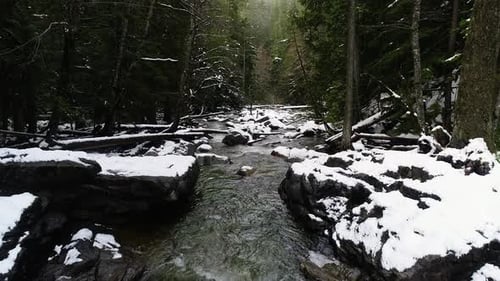Aerial Drone Shot Along River Above Snow Covered Frozen Boulders