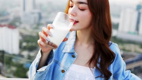 Woman Drinks Milk on Urban Rooftop