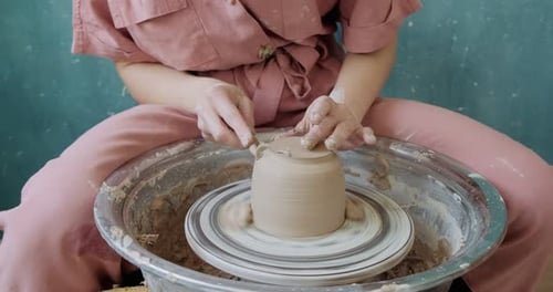 Female Potter Sitting and Makes a Cup on the Pottery Wheel. Woman Making Ceramic Item. Pottery