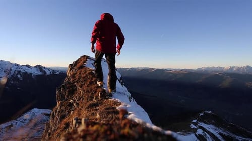 Ein Mann erreicht den Gipfel, nachdem er auf einen schneebedeckten Berg gestiegen ist