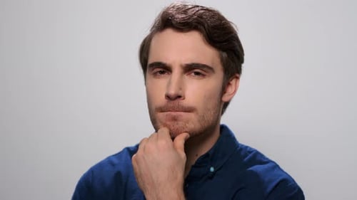 Serious Man Thinking in Studio. Male Student Touching Face with Hand