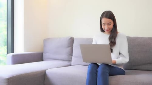 Young Woman Types on Laptop Indoors at Home