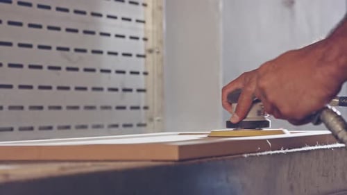 Slow motion of a worker polishing a cabinet door in a furniture factory