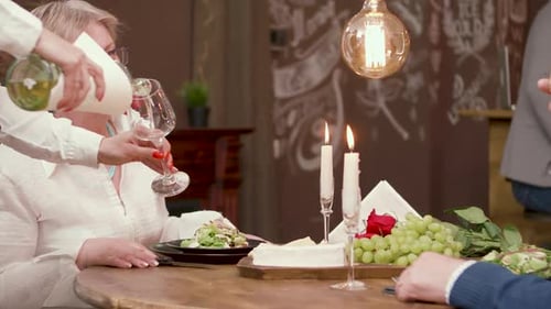 Waiter Pours Wine for Elegant Couple at Restaurant