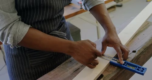 Person Measuring Wood Plank with Ruler and Pencil