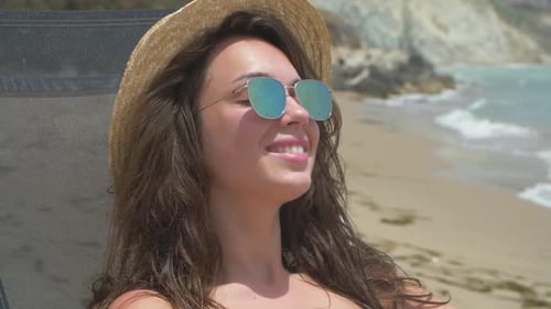 Beautiful Smiling Brunette Female Lying on the Deck Chair on the Beach
