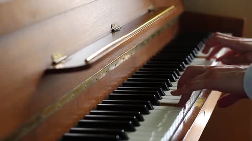 Hands Play a Wooden Piano Indoors
