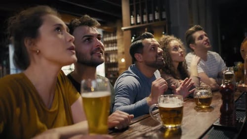Group of friends cheering to soccer match in the pub. Shot with RED helium camera in 8K.