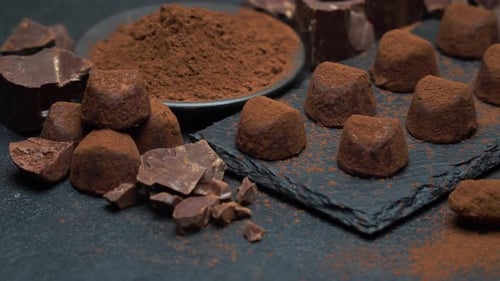 Classic Chocolate Truffles and Pieces of Chocolate on Dark Concrete Background