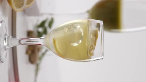 Vertical video, Close-up: lemon falling into a glass of alcohol in slow motion