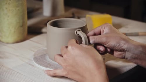 Jeune femme potière attachant un petit morceau d'argile à un bord du manche et à une tasse