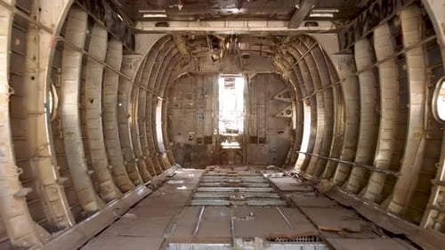 Aerial zoom out drone shot of the inside an old dismantled army plane monument placed on an empty di
