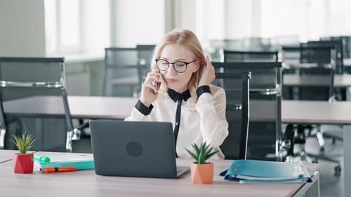 Woman Talking on Phone Working on Laptop