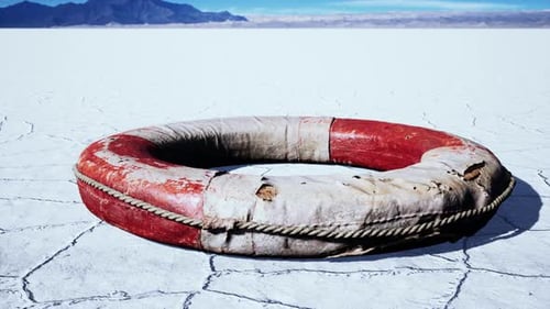 Weathered Lifebuoy on Arid Landscape with Distant Mountains