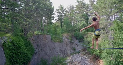 Man Balances on Tightrope Above Rocky Ravine