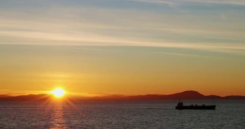 Cargo Ship Sails into Sunrise on Open Ocean