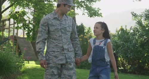 Soldier and Daughter Walking in Yard Holding Hands