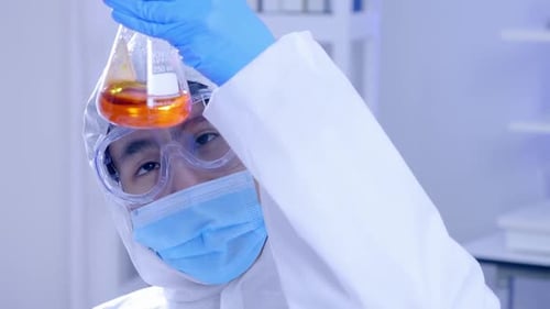 Person Inspecting Orange Solution in Science Lab