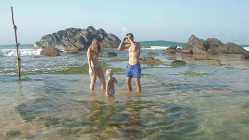 Family Spends Leisure Standing in Transparent Ocean