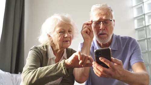 Senior Couple Sharing Smartphone Indoors Together