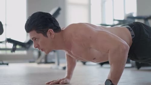 Muscular Young Adult Doing Push Ups in Gym