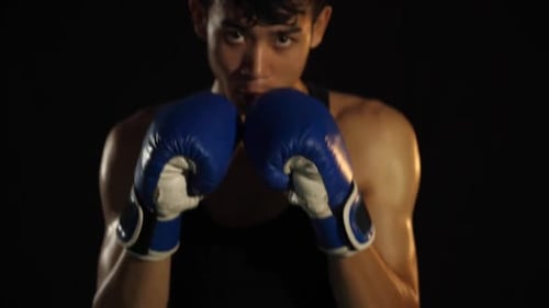 Focused Young Boxer Practicing Punches in the Dark