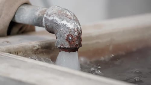 Water Pouring From a Corroded Metal Pipe
