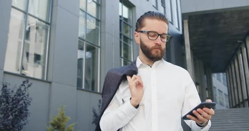 Trabajador Corporativa de pie en el fondo de un edificio urbano moderno y tiene teléfono