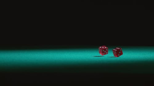 Red Dice Rolling on Green Table in Spotlight