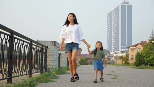 Mother Walks with Korean Little Girl Along Embankment