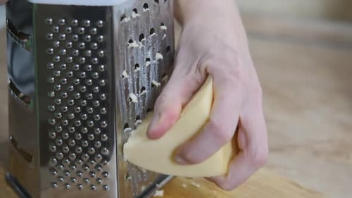 Hands Grating Cheese with a Metal Grater