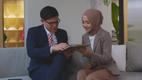 Young asian businessman discussion and planning with secretary while sign document contract.