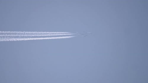 Airplane Flying With White Contrail Across Blue Sky