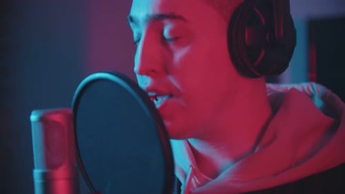 A Man in Headphones Rapping Through the Pop-filter in the Microphone