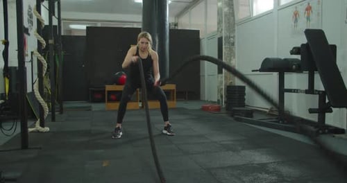 Sport Woman Doing Battle Ropes Exercise at Gym