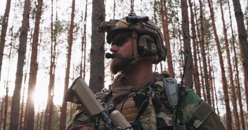 Portrait d'un soldat d'âge moyen barbu dans un uniforme militaire des bois et un casque avec des écouteurs