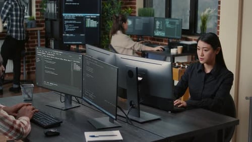 Two Focused Coders Facing Each Other Writing Code in Software Development Office