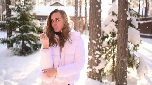 Woman Smiles in Snow Covered Forest as Snow Falls