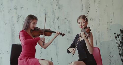 Two Women Perform Violin Duet Indoors