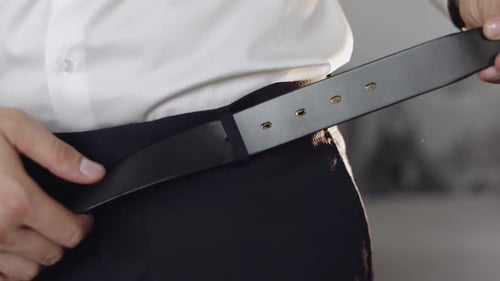 Groom Wears a Belt. Man in White Shirt Puts Belt on His Pants in Wedding Morning