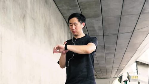Young Adult Checks Fitness Tracker in City