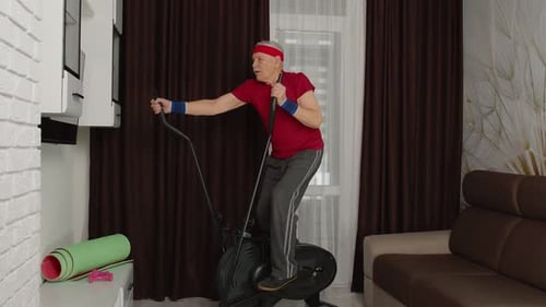 Senior Man Exercising on Elliptical Machine at Home