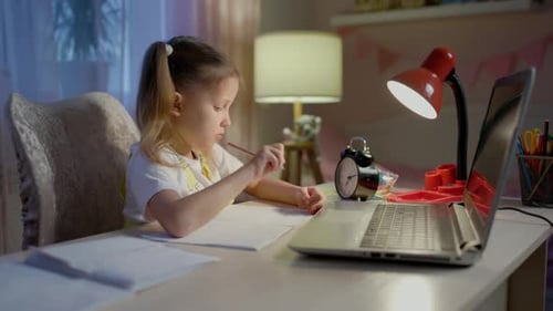 Girl Studying at Desk with Laptop at Night