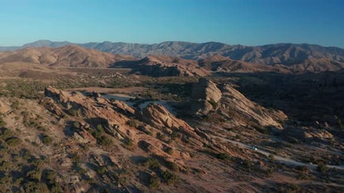 Desert landscape - Aerial footage of mountains and dry land with blue cloudy sky in the background.