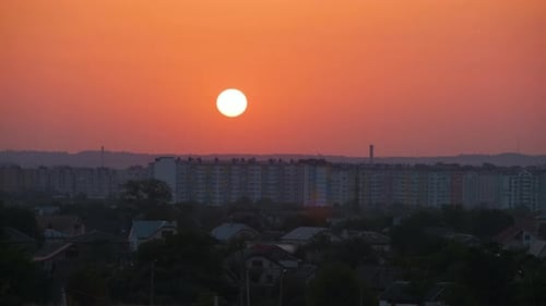 Evening Landscape with Bright Setting Sun Over Distant City High Rise Buildings at Sunset